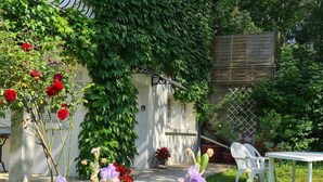 Un jardin avec un mur blanc, une clôture en bois et une chaise blanche.