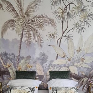 A room with a bed against a wall featuring a tropical mural.