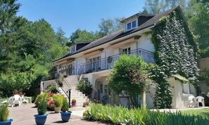 A two-story building with a balcony, surrounded by greenery and potted plants. - Studio "Les Iris - St Martin" with Terraces, Shared Garden, and Wi-Fi (Monthou-sur-Cher)