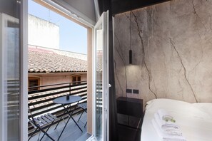 A hotel room with a bed, a small table, and a balcony with a table and chairs. - Bed and Breakfast 'Vicolo Del Fortino - Suite 105' with Balcony, Wi-Fi and Air Conditioning (Catania)