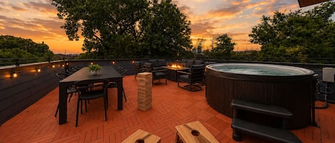 Terraza en la azotea con jacuzzi, zona de estar y mesa de juegos de madera.