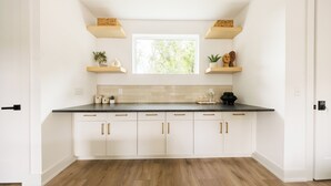 A kitchen with white cabinets, a dark countertop, and a window above the sink. - Nashville Rooftop Home with Hot Tub & Skyline Views (Nashville)