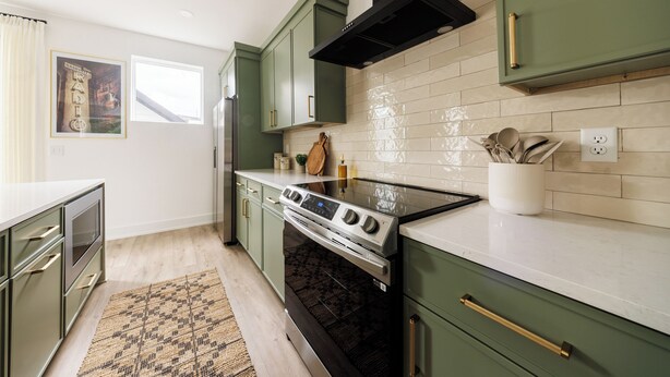 A modern kitchen with green cabinets, a stainless steel refrigerator, a black stove, and a tiled backsplash. - Nashville Rooftop Home with Hot Tub & Skyline Views (Nashville)