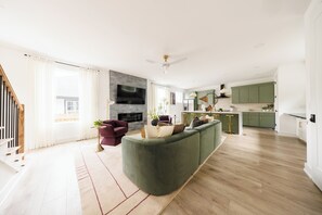 Ein modernes Wohnzimmer mit einem grünen Sofa, einem Flachbildfernseher und einem Kamin.