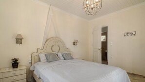 A bedroom with a bed, bedside tables, a nightstand, a lamp, and a hanging light fixture. - Holiday Home 'Evans Terrace Suite' (Nikiana)