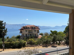 A multi-story building with a red-tiled roof, situated near a body of water with mountains in the background. - Holiday Home 'Evans Terrace Suite' (Nikiana)