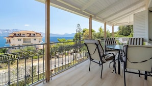 A covered outdoor seating area with a view of the sea and mountains. - Holiday Home 'Evans Terrace Suite' (Nikiana)