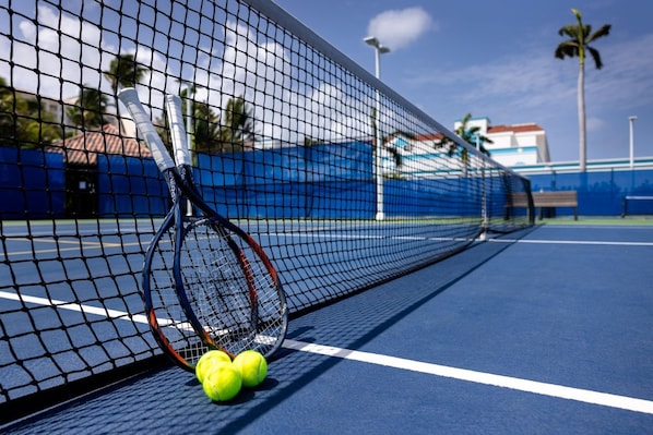 Un court de tennis avec un filet, des raquettes de tennis et des balles de tennis.