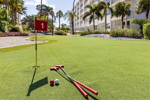 Un putting green de golf con una bandera marcada '1', dos palos de golf y dos pelotas de golf.
