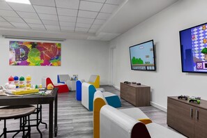 Una sala de reuniones moderna con asientos de colores, un cuadro abstracto grande, un televisor montado y un armario de madera.