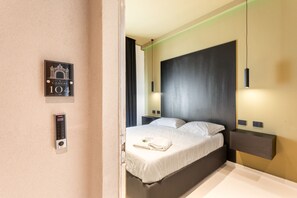 Une chambre d’hôtel avec un lit, un téléphone fixé au mur et une pancarte portant le numéro 101.
