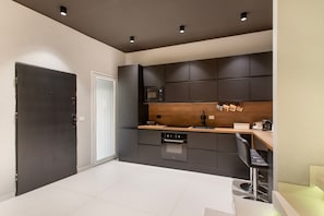 Una cocina moderna con armarios oscuros, encimera de madera y horno empotrado.