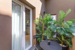 Een balkon met een tafel, stoelen en plantenpotten.