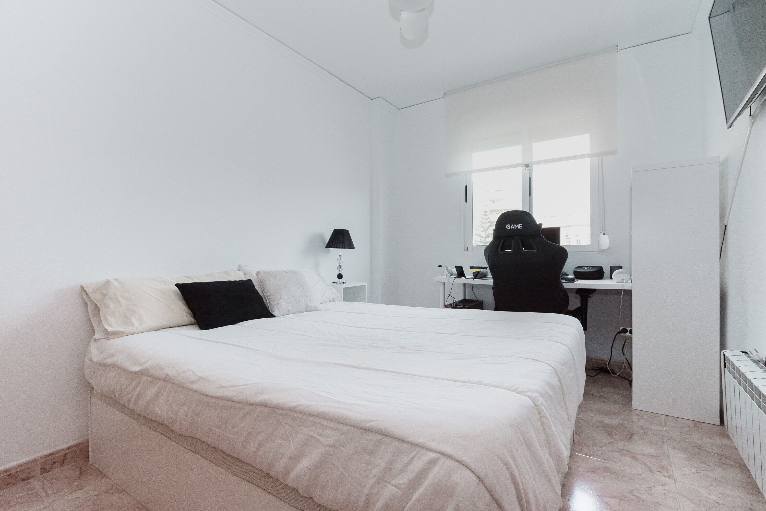 Un dormitorio con cama, escritorio, silla y ventana.