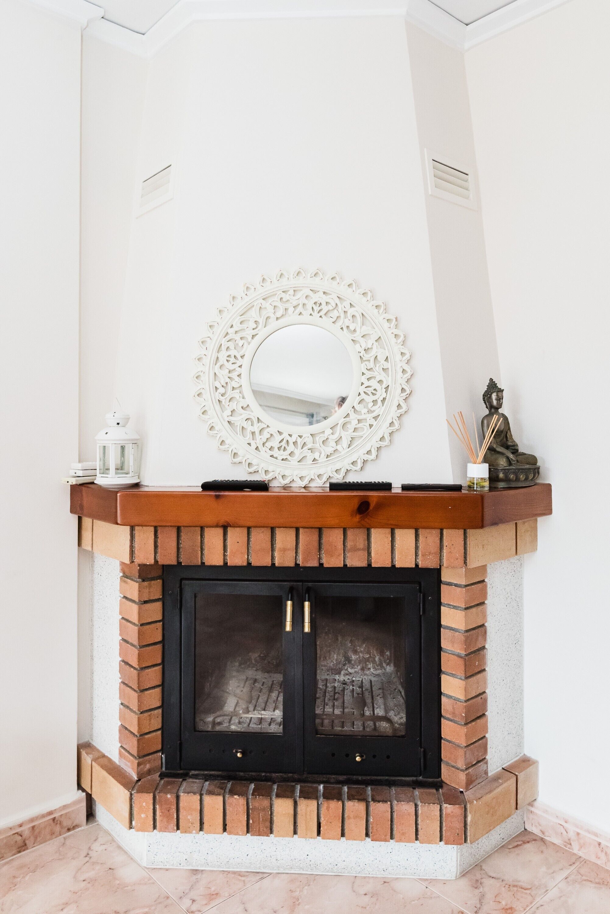 A fireplace with a decorative mirror above it, a small statue, and a lantern on the mantel.