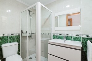 A bathroom with a glass-enclosed shower, a white sink, and a mirror above it.