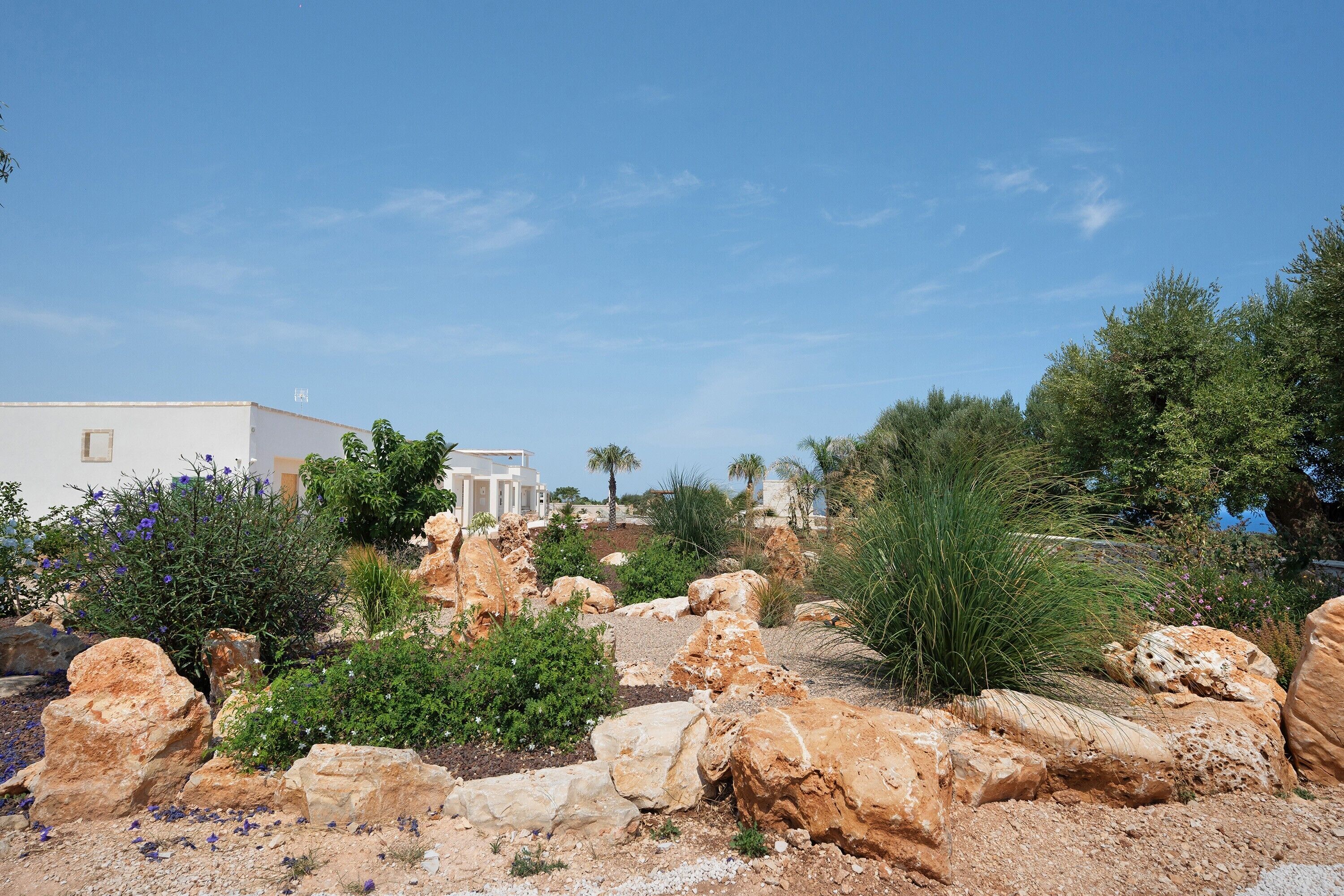A rocky landscape with white buildings and greenery.