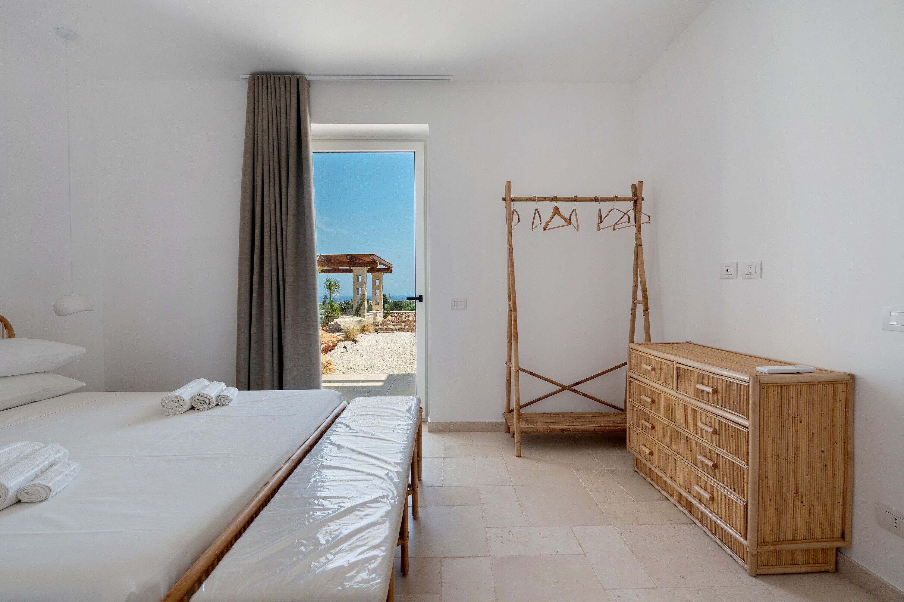 A bedroom with a bed, a wooden dresser, and a wooden drying rack.