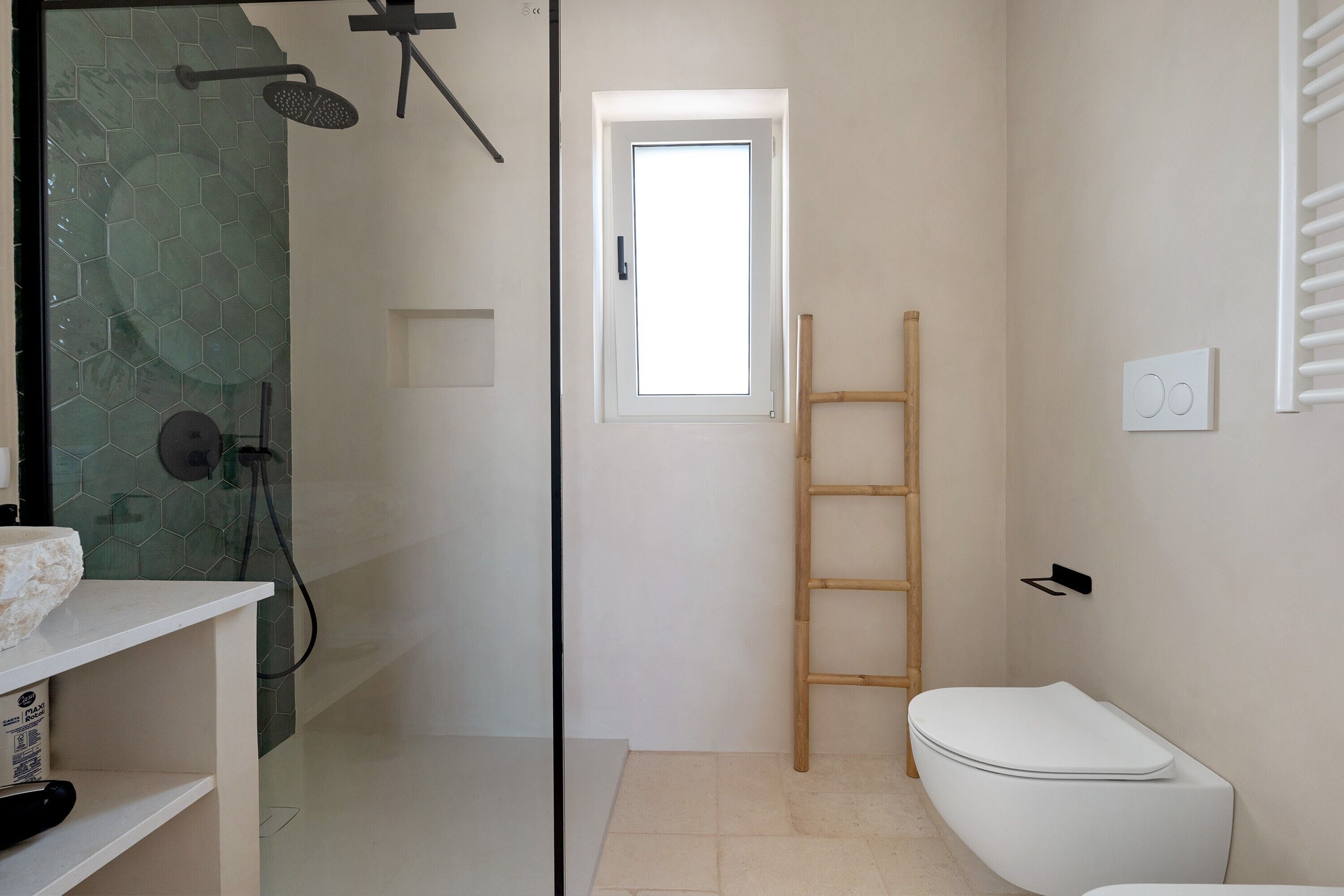 A bathroom with a shower, toilet, and a window.