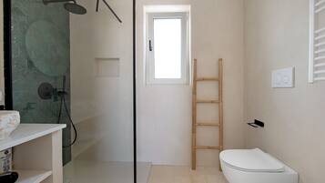A bathroom with a shower, toilet, and a window.