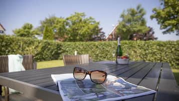 Un magazine et une paire de lunettes de soleil posées sur une table à l’extérieur.