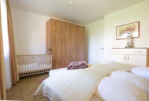 Een slaapkamer met een ledikant, een kledingkast, een bed en een schilderij aan de muur.