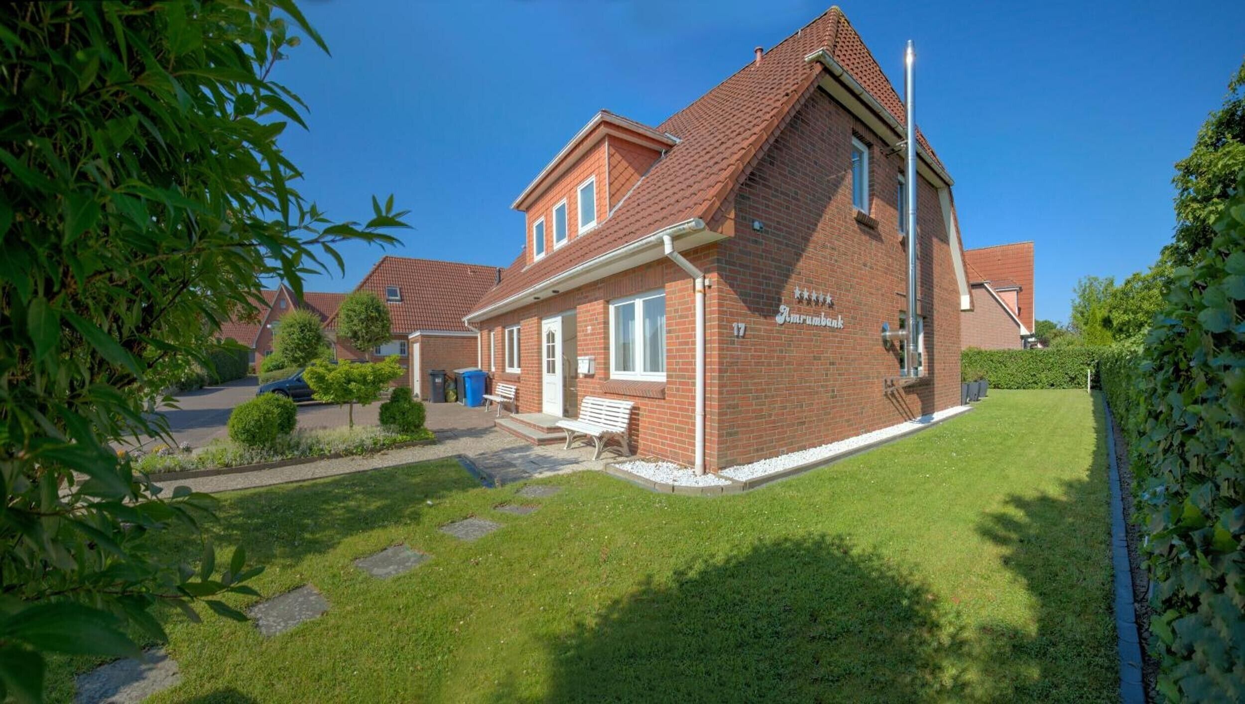 A two-story house with a brick exterior, a tiled roof, and a well-maintained lawn.