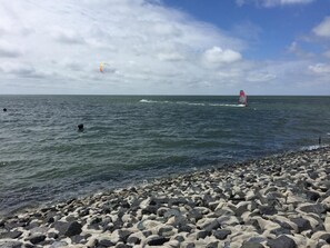 Een rotsachtig strand met een zeilboot op het water.