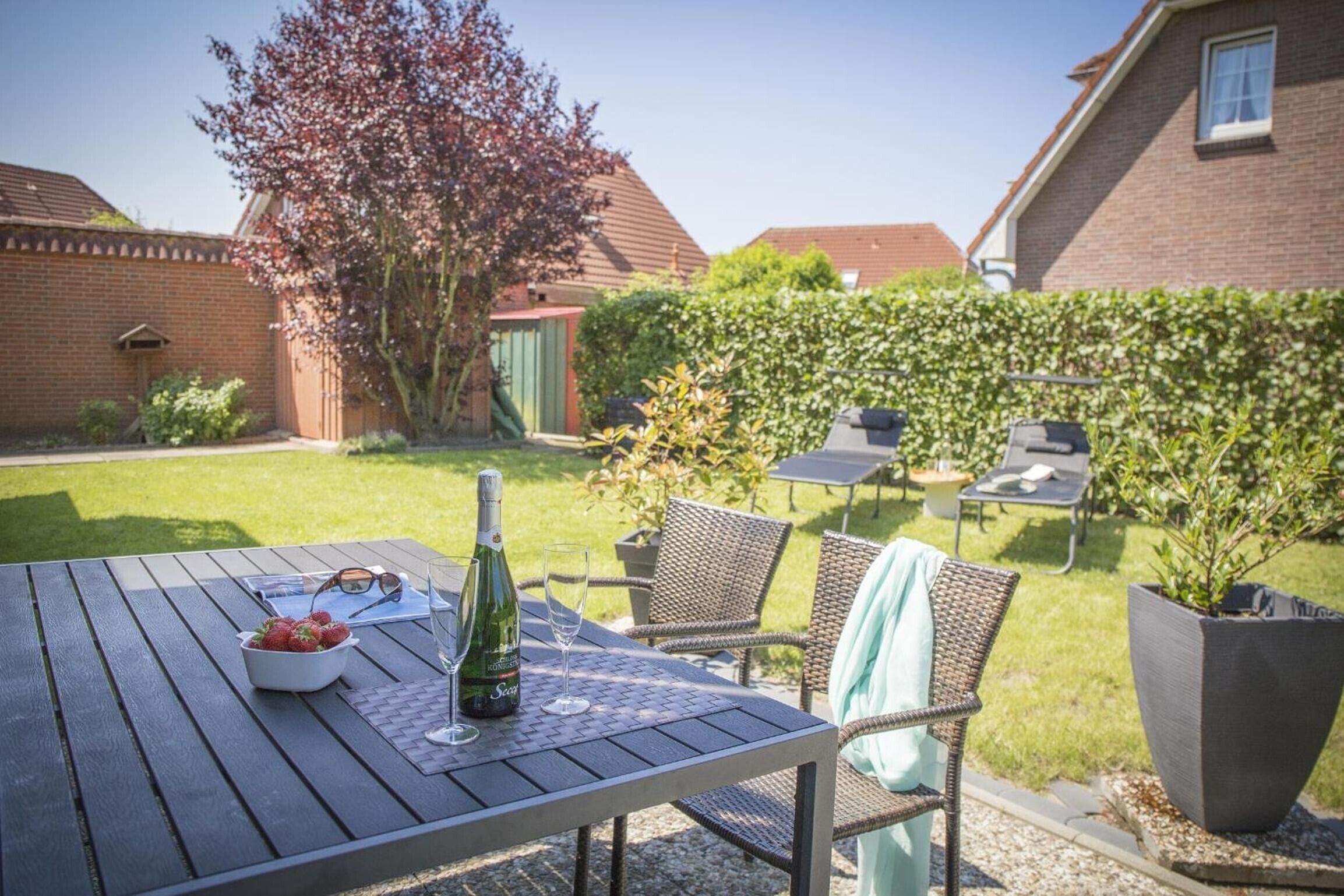 Een terras met een tafel voor twee, een fles wijn en een schaal met aardbeien.