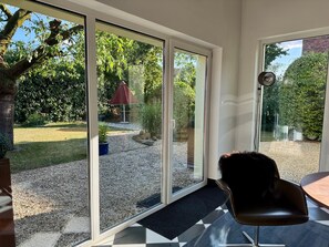 A room with a large sliding glass door leading to a garden with a patio table and chairs. - Holiday Home 'Haus um 1900 – Entire Place for You' with Terrace, Garden & Wi-Fi (Ennigerloh)