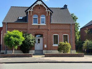 A two-story brick house with a tiled roof, a front door, and two windows on the upper floor. - Holiday Home 'Haus um 1900 – Entire Place for You' with Terrace, Garden & Wi-Fi (Ennigerloh)
