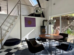 Ein modernes Interieur mit einer Treppe, einem runden Esstisch und einer gemütlichen Sitzecke.