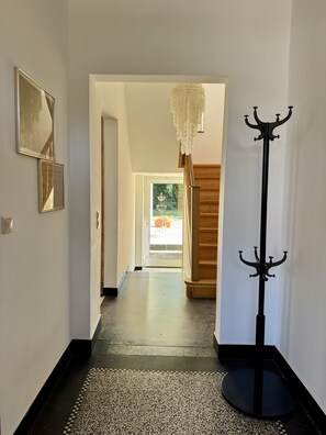 Ein Flur mit Kleiderständer, einer Tür zu einem Zimmer und einer Treppe.