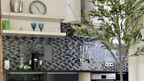 Uma cozinha moderna com piso xadrez preto e branco, uma cafeteira e uma cesta de vime com rodinhas.