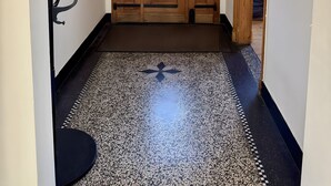 Um corredor com uma porta de madeira, um cabide e um chão estampado.