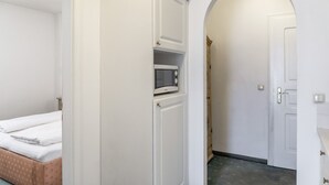 A bedroom with a bed, a wardrobe, a microwave, and an arched doorway. - Apartment “Grattschlössl 1” with Mountain View, Balcony, and Wi-Fi (Sankt Johann)