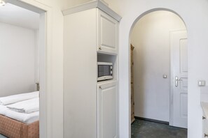 A bedroom with a bed, a wardrobe, a microwave, and an arched doorway. - Apartment “Grattschlössl 1” with Mountain View, Balcony, and Wi-Fi (Sankt Johann)