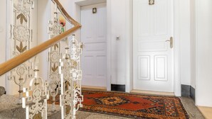 A staircase with ornate metal railings, a patterned carpet, and a white door with a number plate. - Apartment “Grattschlössl 1” with Mountain View, Balcony, and Wi-Fi (Sankt Johann)