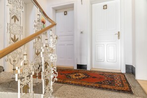 A staircase with ornate metal railings, a patterned carpet, and a white door with a number plate. - Apartment “Grattschlössl 1” with Mountain View, Balcony, and Wi-Fi (Sankt Johann)