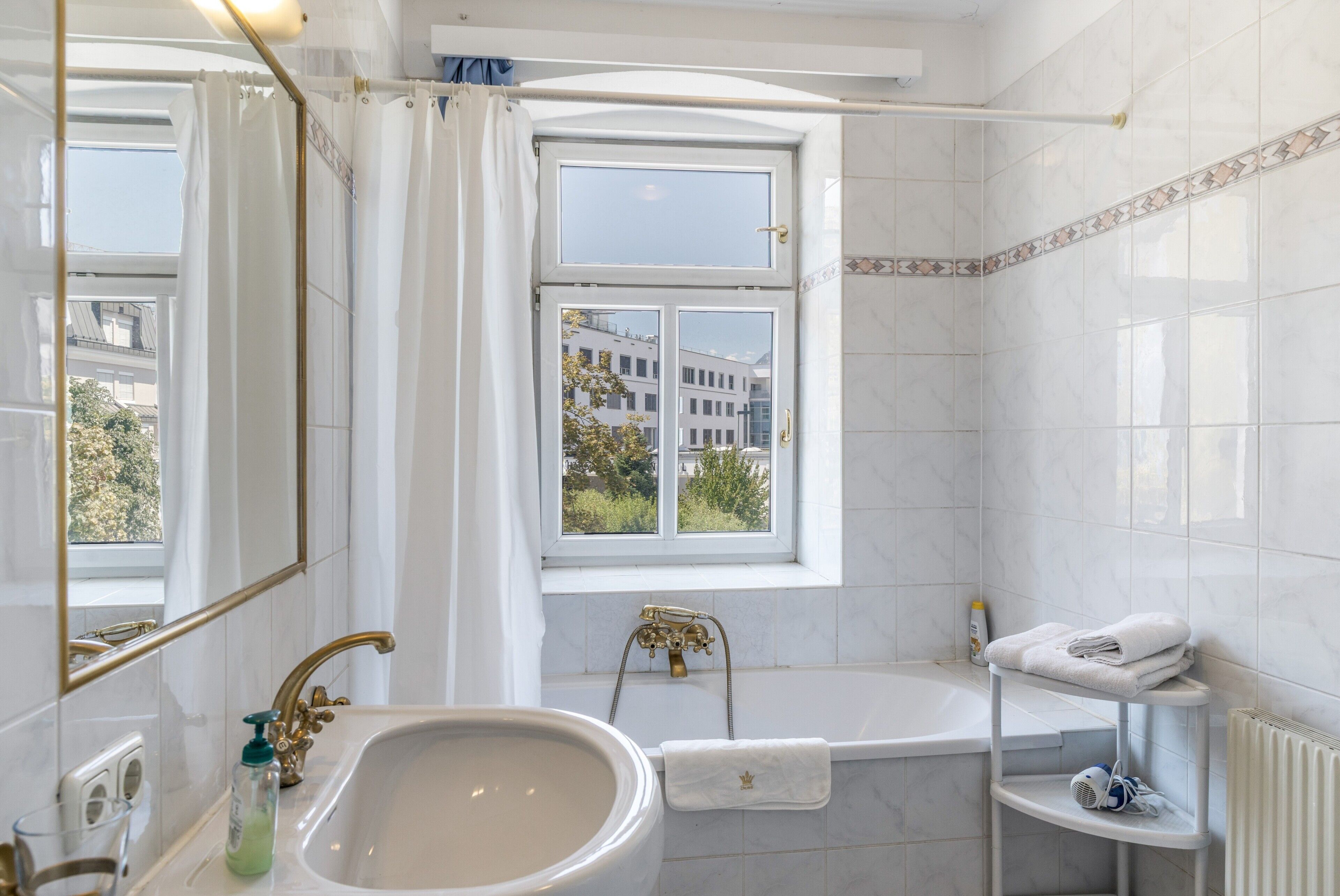 Een badkamer met een badkuip, wastafel, raam en handdoekhouder.