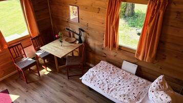 Ein Zimmer in einer Holzhütte mit einem Bett, einem Tisch und Stühlen.