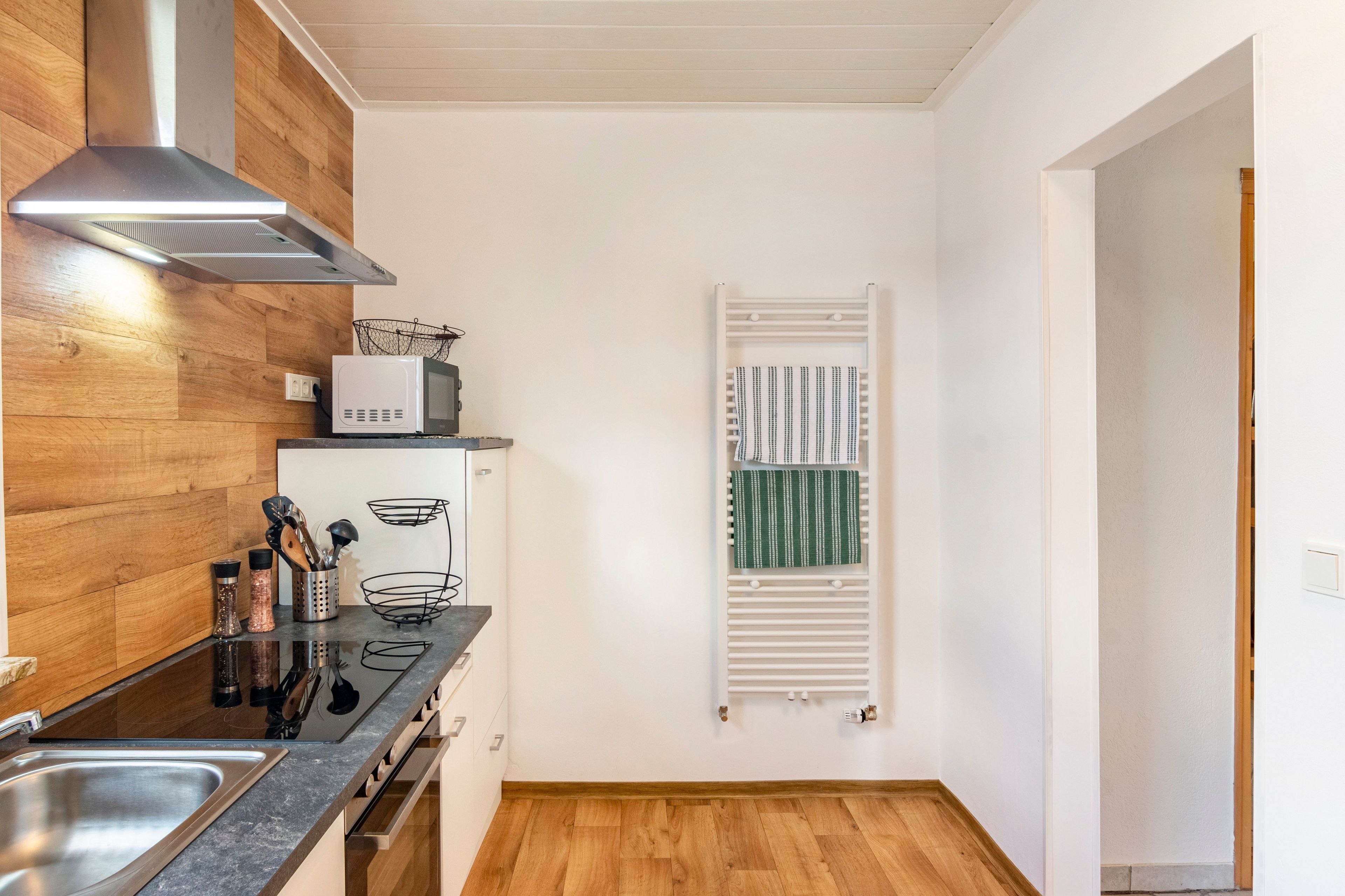 A modern kitchen with a stainless steel sink, wooden cabinets, and a built-in microwave.