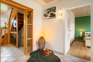Un escalier menant à un deuxième étage, une lampe fixée au mur et un lit dans une pièce aux murs verts.