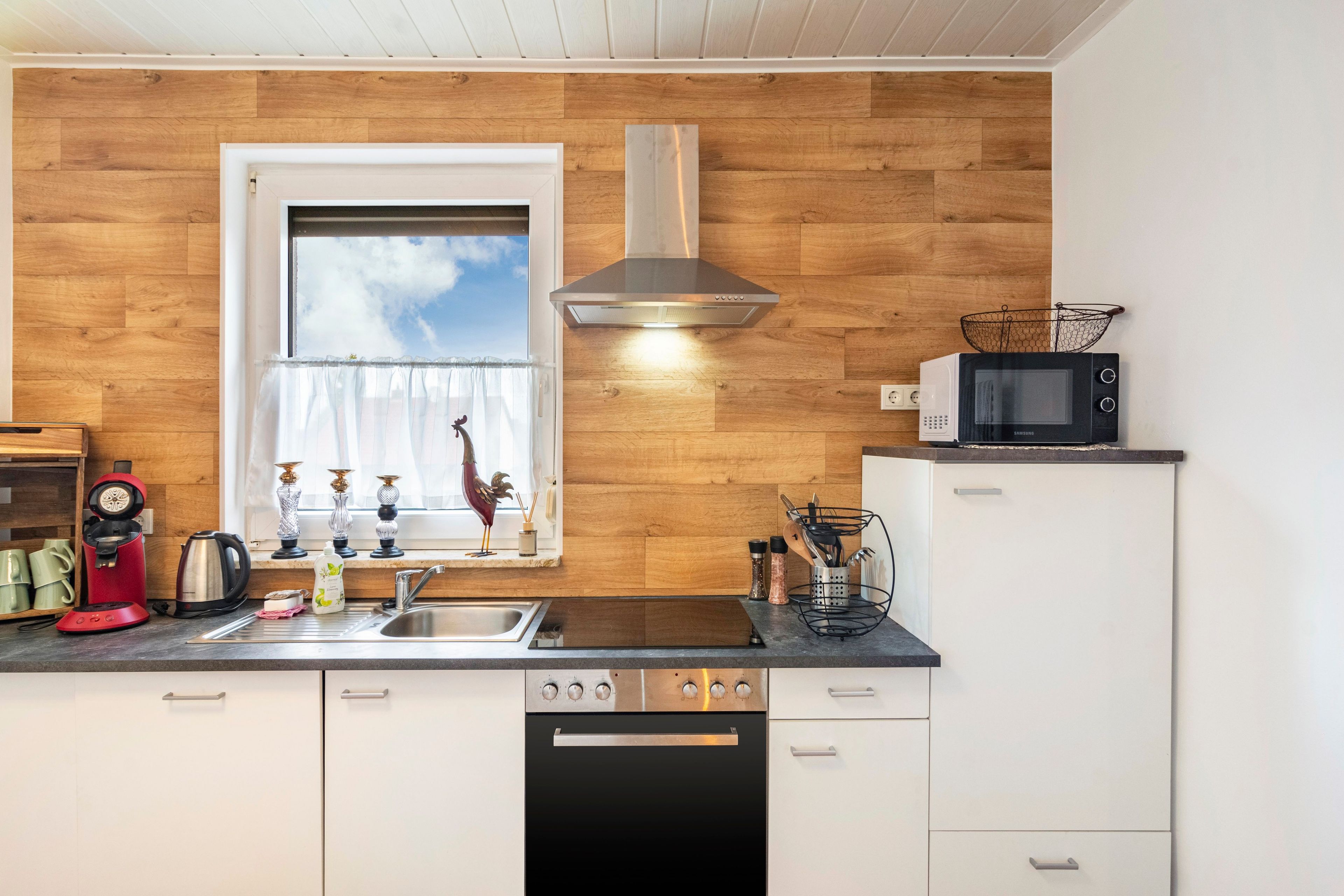 A compact kitchen with a window, a microwave, a coffee maker, and a sink.