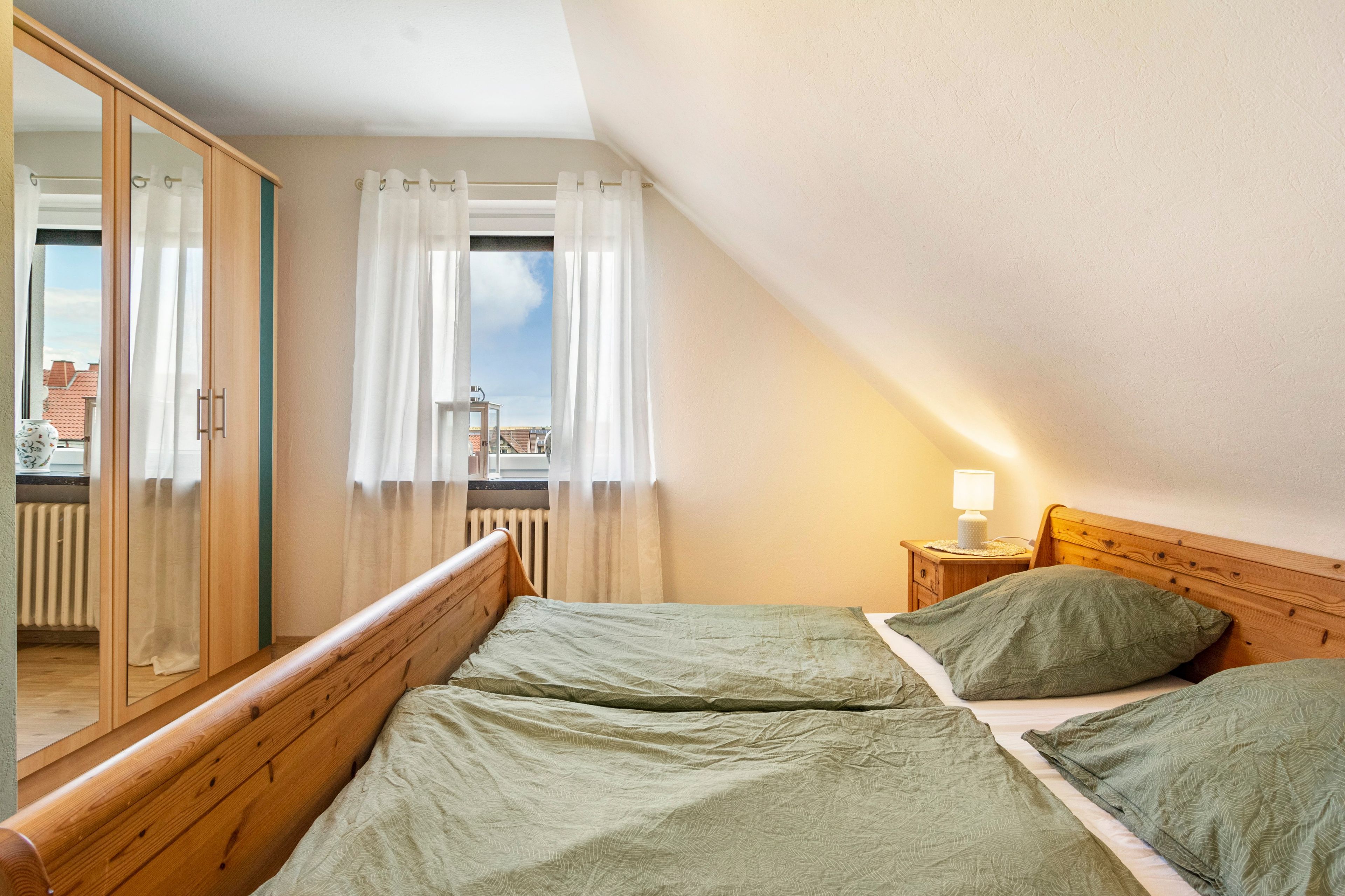 Un dormitorio con una cama de madera, una mesita de noche, una lámpara y vistas al exterior.