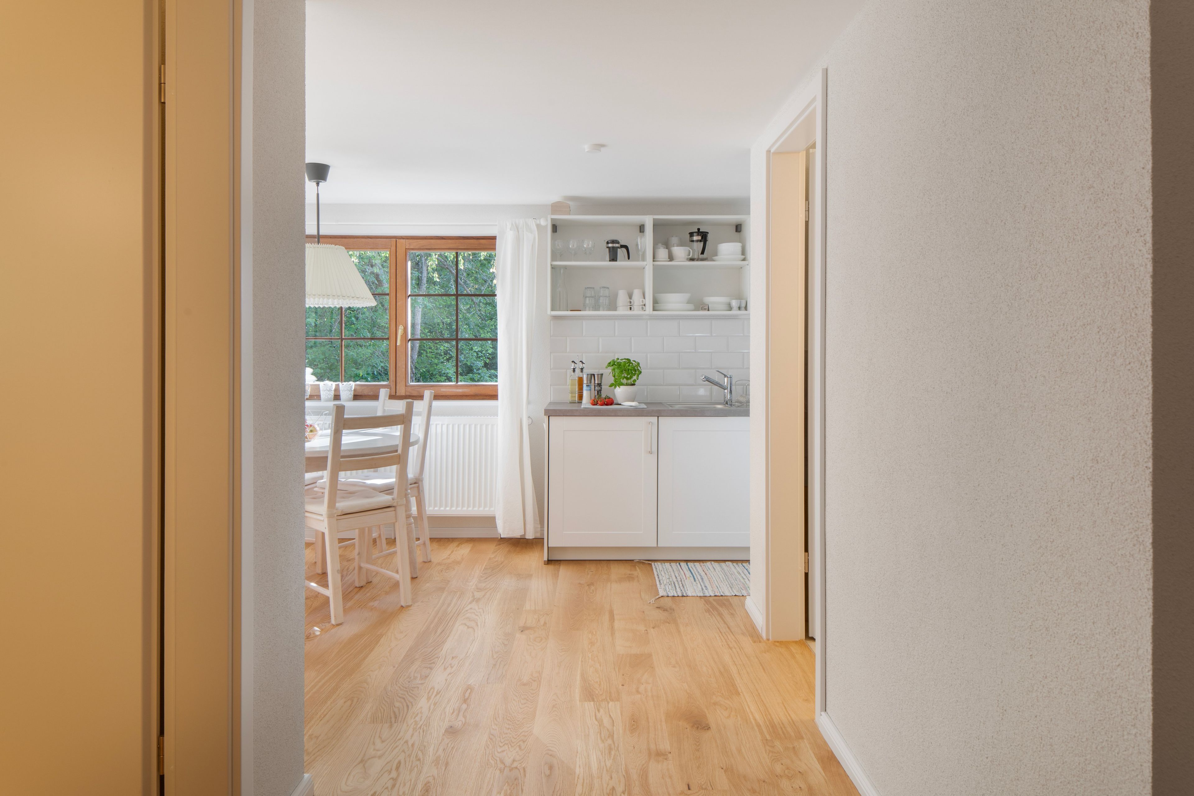 Eine moderne Küche mit weißen Schränken, einer Spüle und einem Fenster mit Blick auf einen Garten.