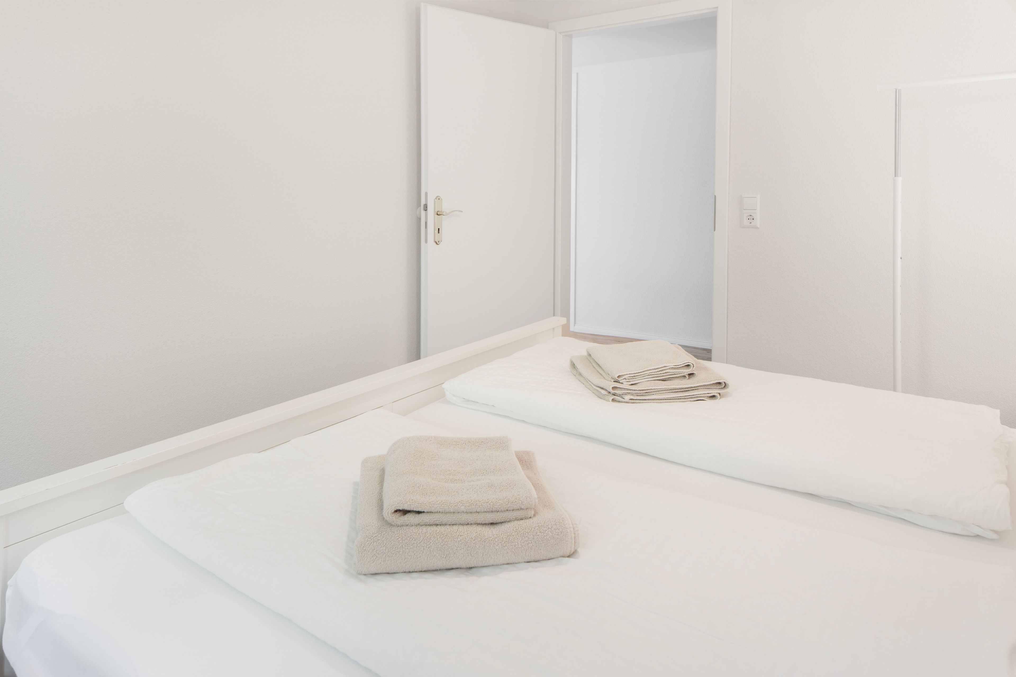 A single bed with a white mattress and two folded towels.