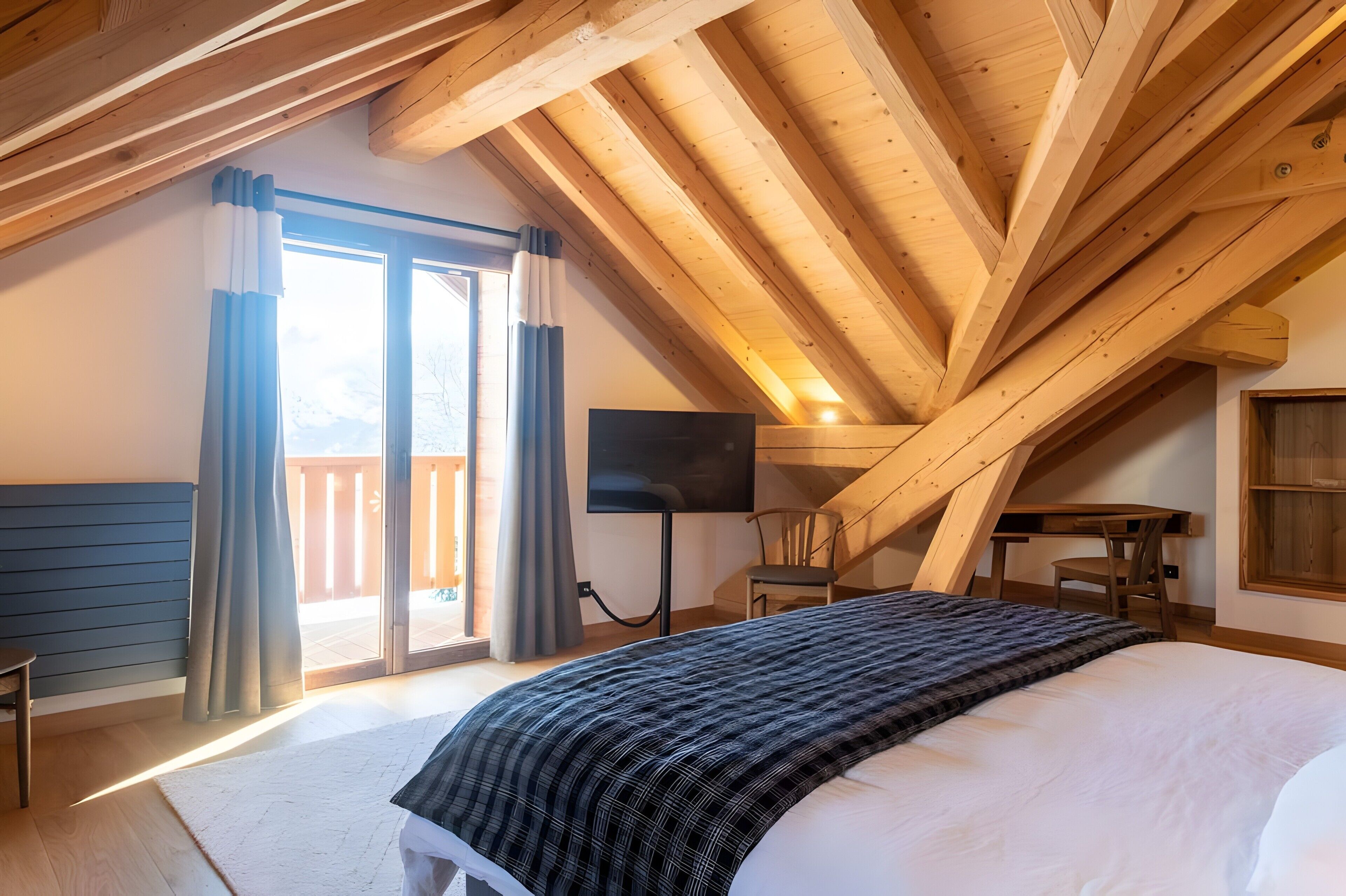 Een slaapkamer met een groot bed, een flatscreen televisie, een houten bureau en een stoel.
