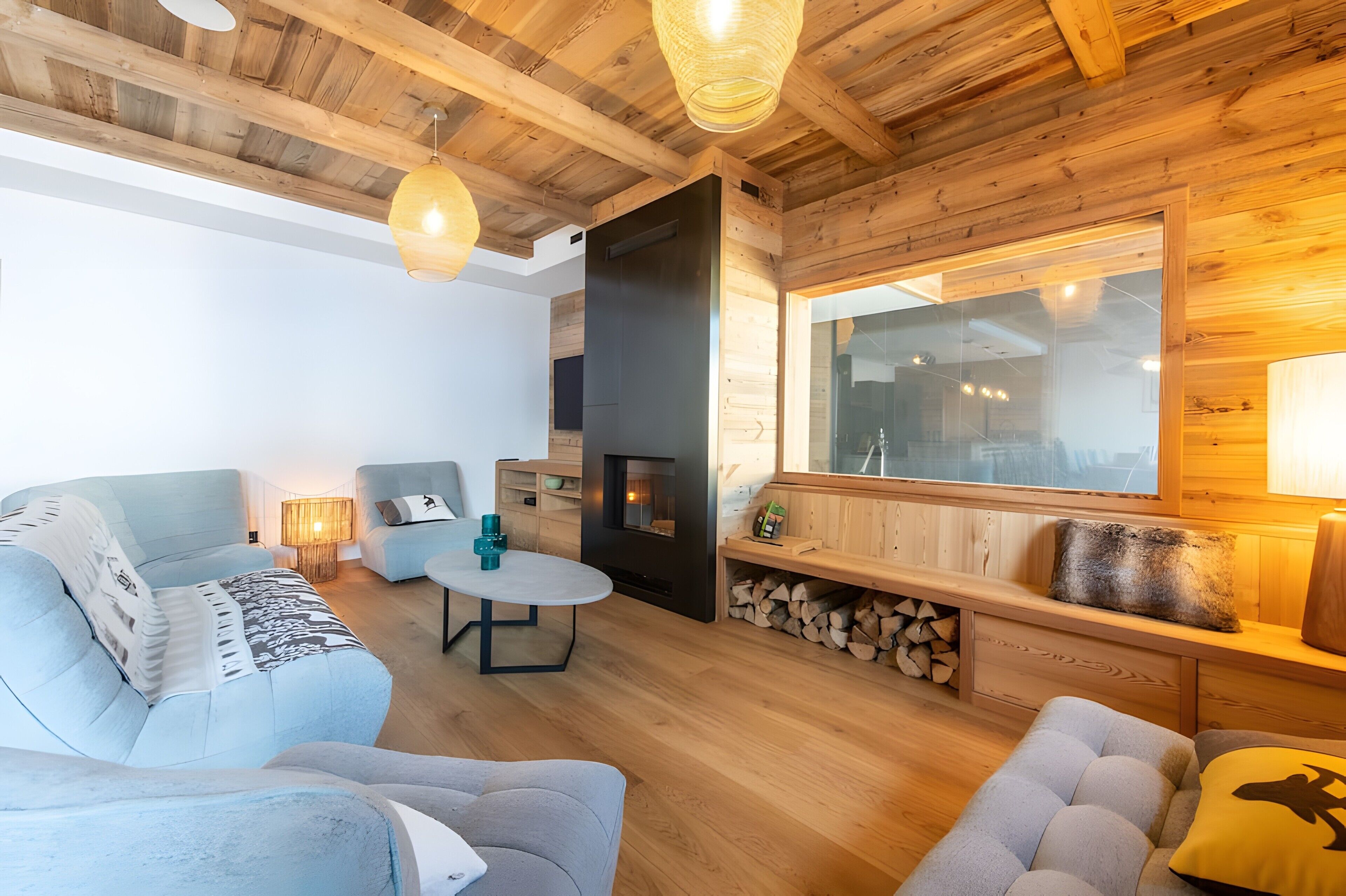 Una sala de estar acogedora con chimenea, vigas de madera y un ventanal grande.
