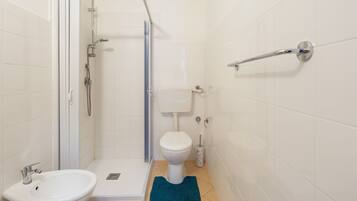 Une salle de bain équipée d’une douche, de toilettes, d’un bidet et d’un lavabo.